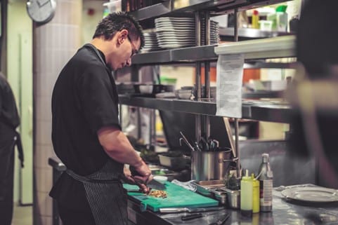 Uomo che cucina in un ristorante riscaldato con bombole gpl